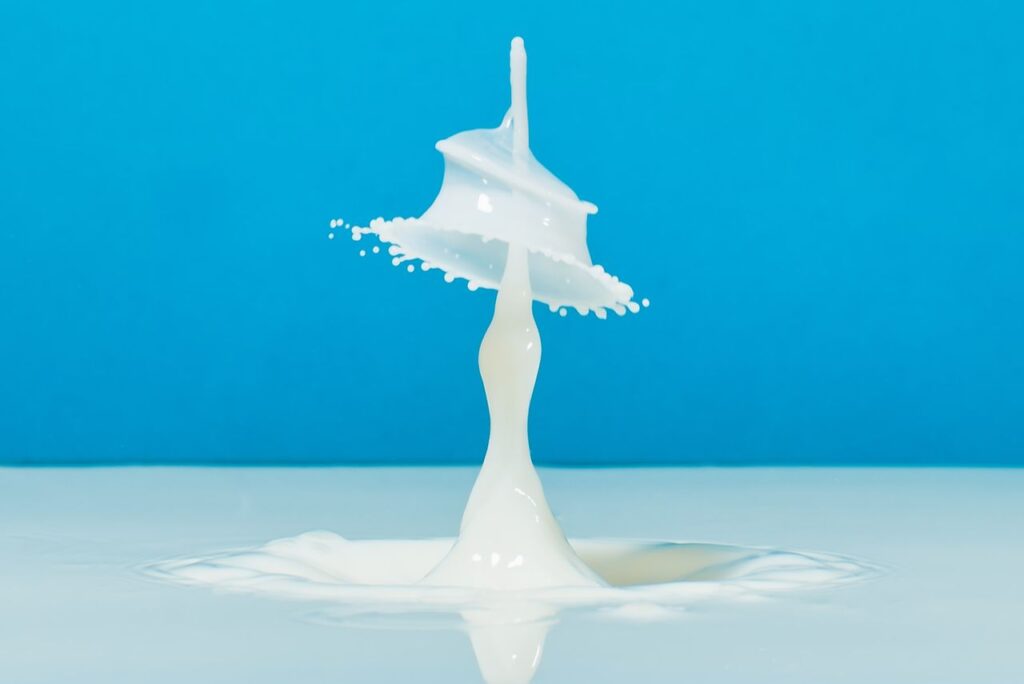 Dynamic close-up of a milk splash creating an artistic liquid shape on a blue backdrop.