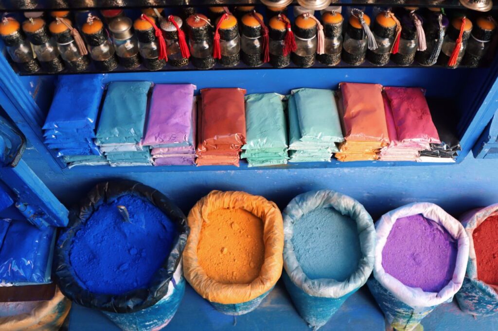 Brightly colored pigment powders neatly arranged in bags and packets at a local market.